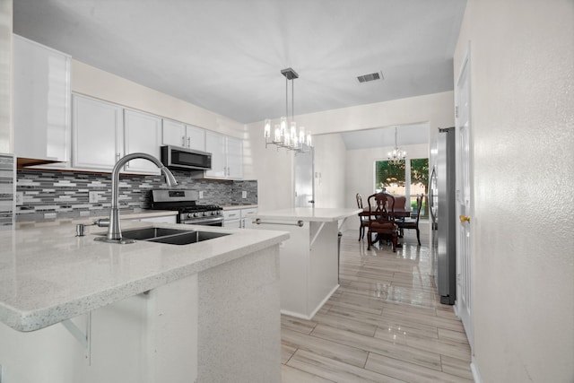 8006 Saffron Ln, Baytown, TX 77521 - kitchen with appliances with stainless steel finishes, a peninsula, a chandelier, backsplash, and a sink