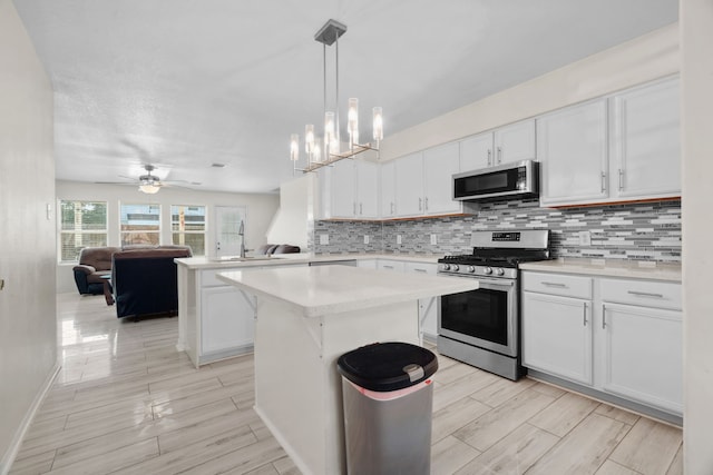 8006 Saffron Ln, Baytown, TX 77521 - kitchen featuring appliances with stainless steel finishes, open floor plan, decorative backsplash, light countertops, and white cabinetry