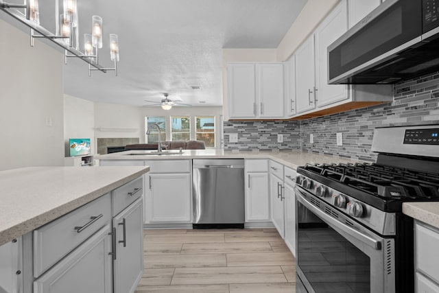 8006 Saffron Ln, Baytown, TX 77521 - kitchen featuring appliances with stainless steel finishes, a sink, a tiled fireplace, and backsplash