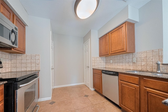 2211 S Kirkwood Rd Unit 19, Houston, TX 77077 - kitchen featuring appliances with stainless steel finishes, a sink, tasteful backsplash, brown cabinetry, and light tile patterned floors