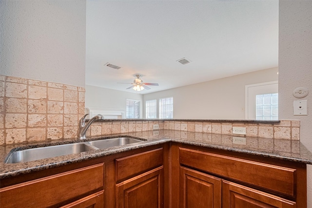 2211 S Kirkwood Rd Unit 19, Houston, TX 77077 - kitchen with a sink, dark stone counters, a ceiling fan, brown cabinets, and decorative backsplash