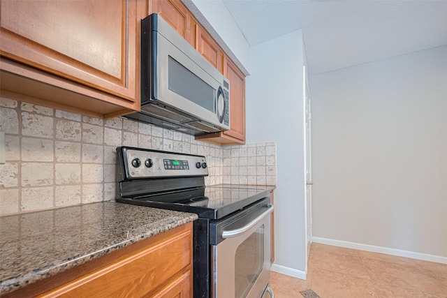 2211 S Kirkwood Rd Unit 19, Houston, TX 77077 - kitchen with appliances with stainless steel finishes, tasteful backsplash, brown cabinets, stone countertops, and baseboards