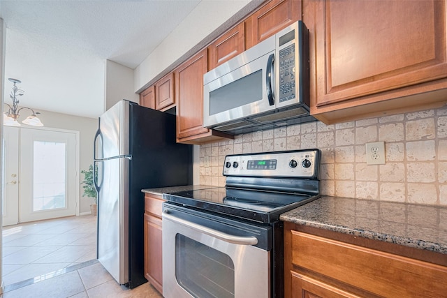 2211 S Kirkwood Rd Unit 19, Houston, TX 77077 - kitchen with appliances with stainless steel finishes, brown cabinetry, light tile patterned floors, and backsplash