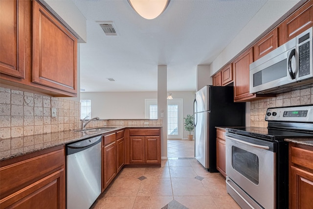 2211 S Kirkwood Rd Unit 19, Houston, TX 77077 - kitchen featuring appliances with stainless steel finishes, a sink, brown cabinetry, backsplash, and light tile patterned floors