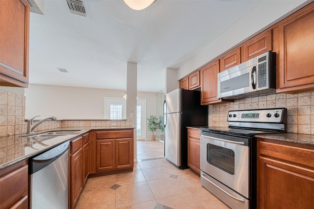2211 S Kirkwood Rd Unit 19, Houston, TX 77077 - kitchen with stainless steel appliances, brown cabinetry, a sink, and backsplash