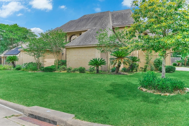 view of side of property with roof with shingles, a lawn, and brick siding