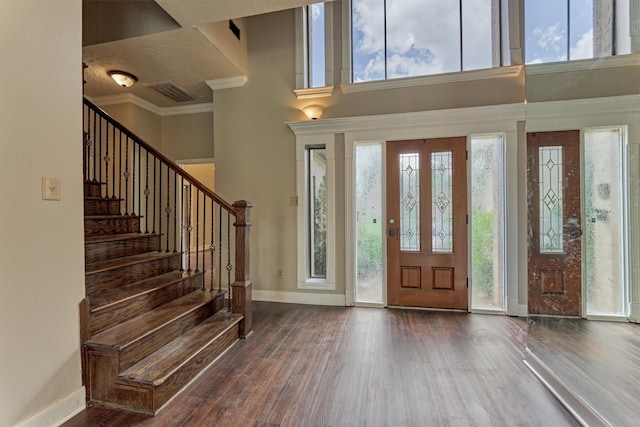 entryway featuring healthy amount of natural light, wood finished floors, stairway, baseboards, and crown molding
