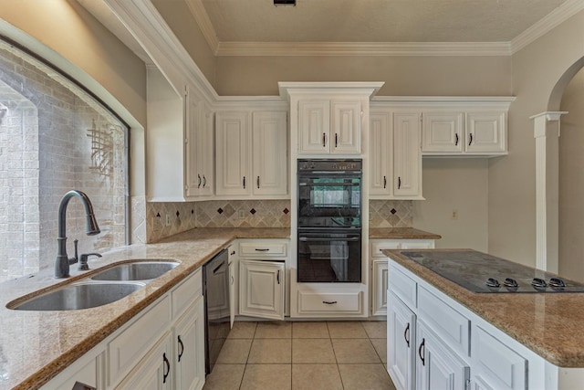 kitchen featuring black appliances, a sink, light stone countertops, arched walkways, and decorative backsplash