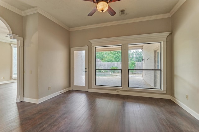 empty room featuring arched walkways, dark wood-style flooring, a ceiling fan, baseboards, and ornamental molding
