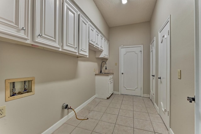 washroom with hookup for a washing machine, cabinet space, light tile patterned floors, and baseboards