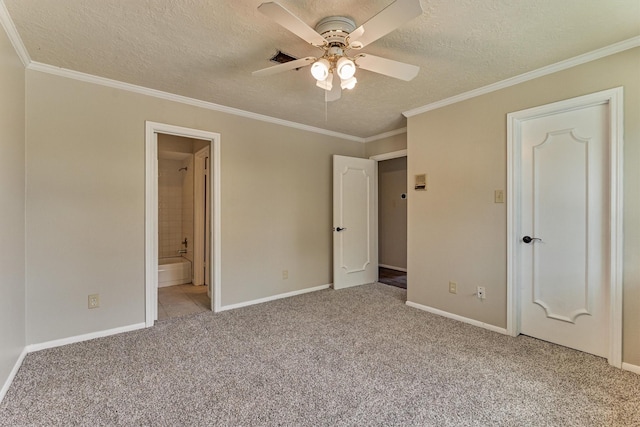 unfurnished bedroom featuring carpet flooring, a textured ceiling, baseboards, ornamental molding, and ensuite bathroom