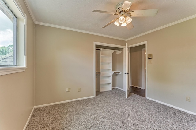 unfurnished bedroom featuring carpet flooring, baseboards, ornamental molding, ceiling fan, and a closet