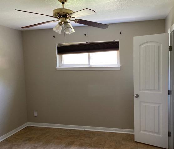 404 Friery St, Dayton, TX 77535 - empty room featuring a ceiling fan, plenty of natural light, and baseboards