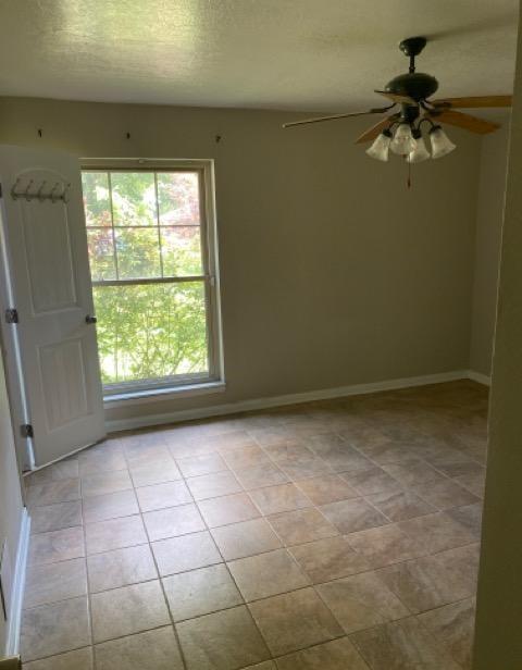 404 Friery St, Dayton, TX 77535 - unfurnished room with light tile patterned flooring, a ceiling fan, a textured ceiling, and baseboards