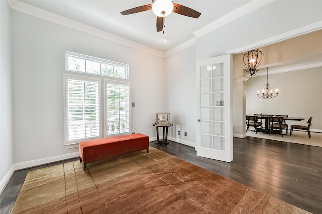 sitting room with hardwood / wood-style flooring, ornamental molding, a ceiling fan, a chandelier, and baseboards