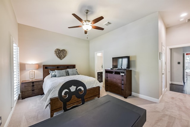 bedroom featuring light colored carpet, baseboards, a ceiling fan, and connected bathroom