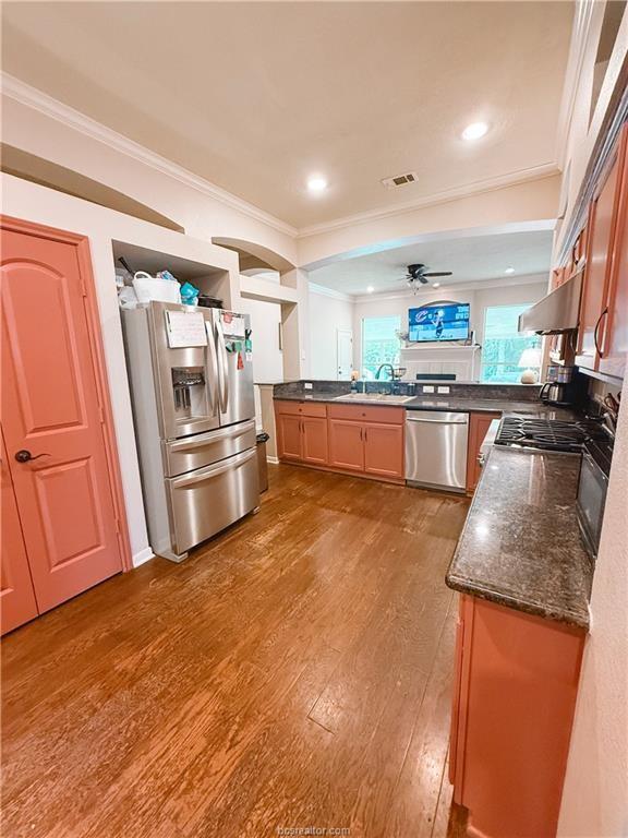 52 Fairway Dr, Normangee, TX 77871 - kitchen featuring appliances with stainless steel finishes, ornamental molding, wood finished floors, a sink, and under cabinet range hood