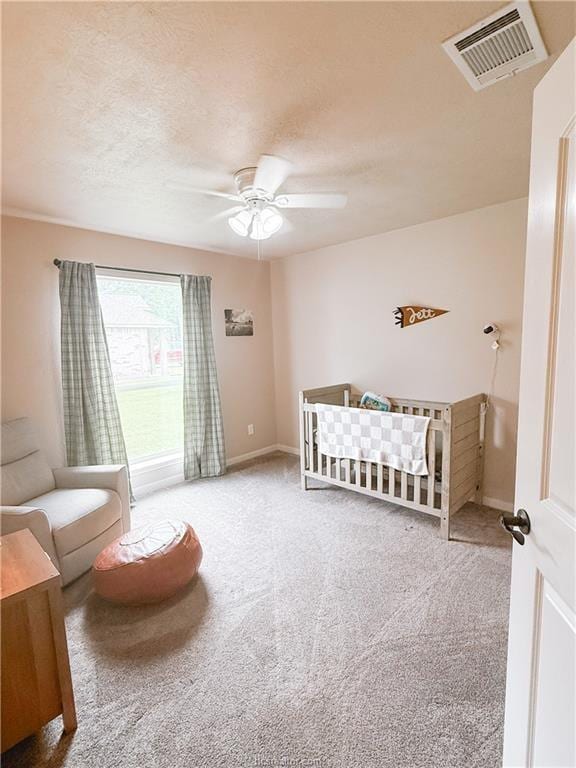 52 Fairway Dr, Normangee, TX 77871 - bedroom featuring carpet, a nursery area, baseboards, a ceiling fan, and a textured ceiling