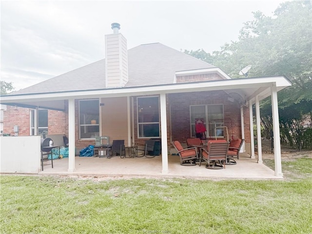 52 Fairway Dr, Normangee, TX 77871 - rear view of house featuring brick siding, a patio, a yard, and a chimney