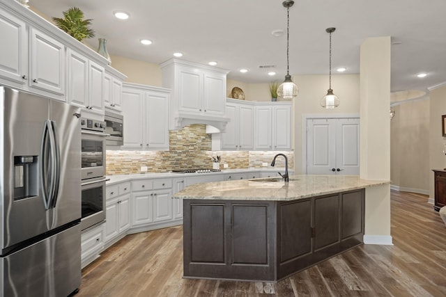 146 Painted Trillium Dr, Conroe, TX 77304 - kitchen with appliances with stainless steel finishes, a sink, white cabinetry, tasteful backsplash, and recessed lighting