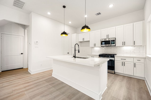 747 Dumble St, Houston, TX 77023 - kitchen featuring range with gas cooktop, stainless steel microwave, a sink, white cabinetry, and recessed lighting