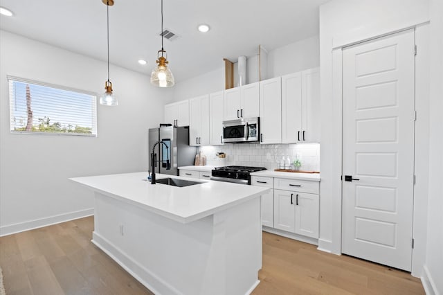 5814 Highland Sky Ln, Houston, TX 77091 - kitchen with appliances with stainless steel finishes, light wood finished floors, backsplash, a center island with sink, and white cabinets