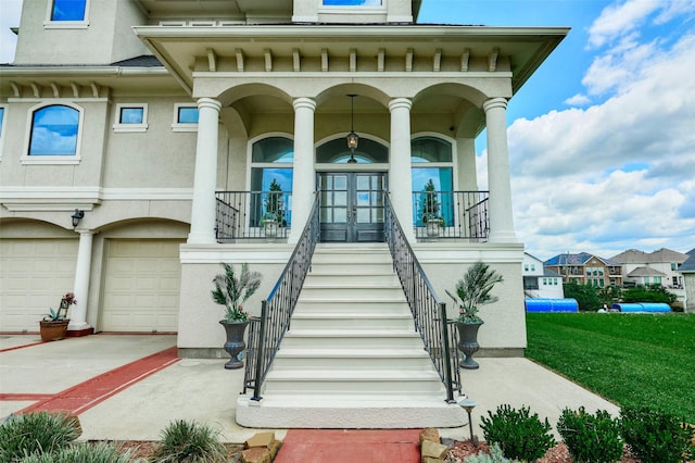 12590 St Ann Ct, Willis, TX 77318 - view of exterior entry featuring french doors, stucco siding, covered porch, a garage, and a lawn