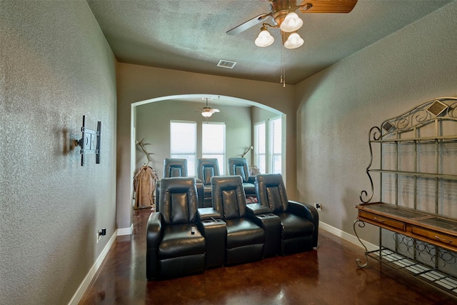 12590 St Ann Ct, Willis, TX 77318 - cinema with a textured wall, arched walkways, concrete flooring, a ceiling fan, and baseboards