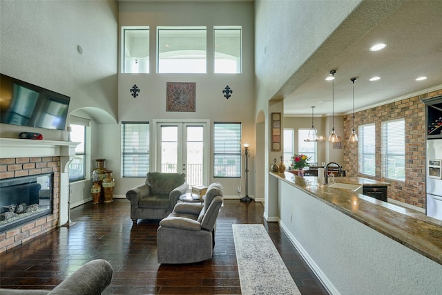 12590 St Ann Ct, Willis, TX 77318 - living area with a brick fireplace, dark wood finished floors, baseboards, recessed lighting, and arched walkways