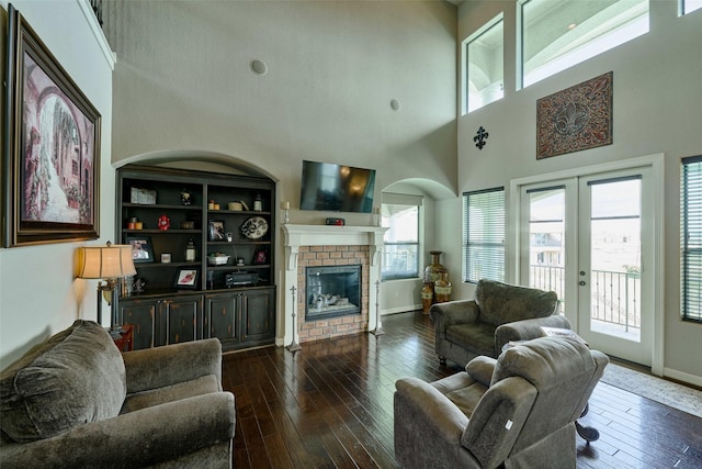 12590 St Ann Ct, Willis, TX 77318 - living area featuring plenty of natural light, a towering ceiling, a fireplace, dark wood-style flooring, and baseboards