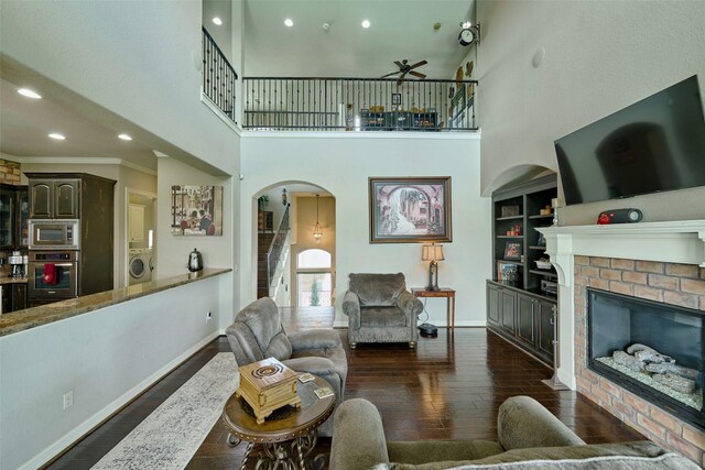 12590 St Ann Ct, Willis, TX 77318 - living room featuring washer / dryer, ceiling fan, dark wood-style floors, arched walkways, and baseboards