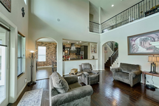12590 St Ann Ct, Willis, TX 77318 - living area with arched walkways, baseboards, a high ceiling, and hardwood / wood-style flooring