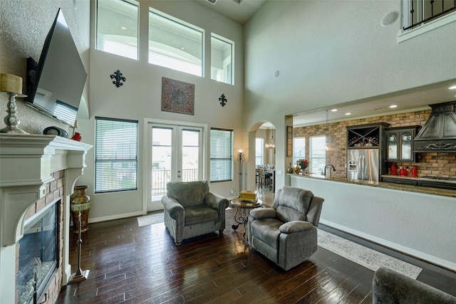 12590 St Ann Ct, Willis, TX 77318 - living room with a glass covered fireplace, baseboards, arched walkways, healthy amount of natural light, and a high ceiling