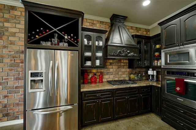 12590 St Ann Ct, Willis, TX 77318 - kitchen featuring stainless steel appliances, crown molding, custom range hood, glass insert cabinets, and light stone countertops
