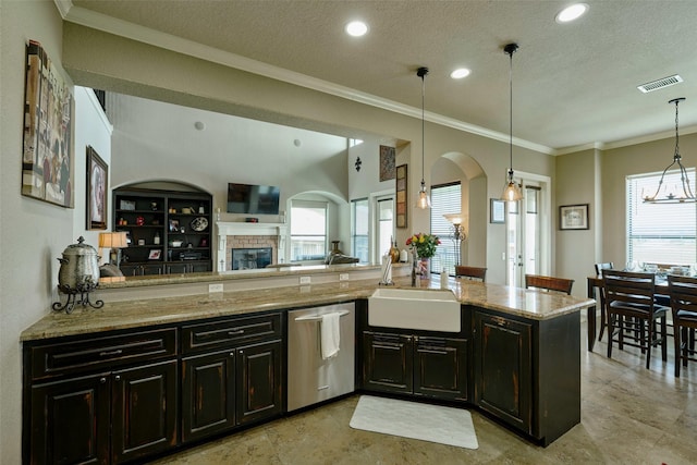 12590 St Ann Ct, Willis, TX 77318 - kitchen with stainless steel dishwasher, a sink, arched walkways, light stone counters, and a fireplace