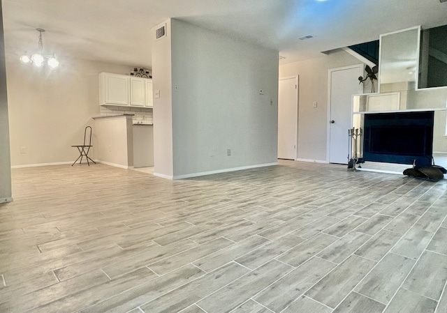 2711 Grants Lake Blvd Unit 203, Sugar Land, TX 77479 - unfurnished living room with light wood-style flooring, baseboards, a fireplace with raised hearth, and a chandelier