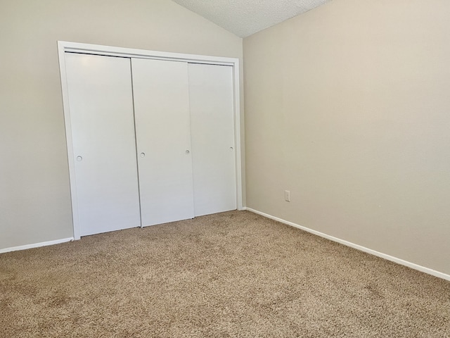 2711 Grants Lake Blvd Unit 203, Sugar Land, TX 77479 - unfurnished bedroom with carpet, a closet, lofted ceiling, a textured ceiling, and baseboards