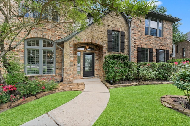 property entrance with a lawn and brick siding