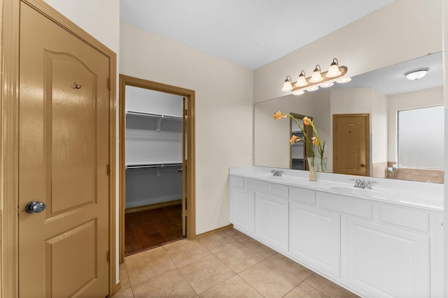 bathroom with double vanity, tile patterned flooring, a spacious closet, and baseboards