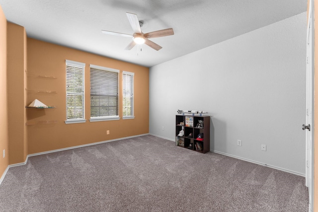 carpeted empty room featuring ceiling fan and baseboards