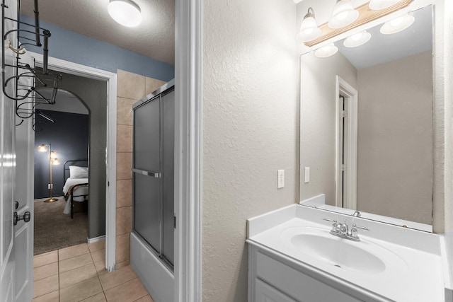 full bath featuring tile patterned flooring, vanity, a textured ceiling, bath / shower combo with glass door, and a textured wall
