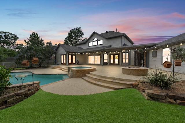 rear view of house featuring french doors, a fire pit, a patio area, an in-ground hot tub, and roof with shingles