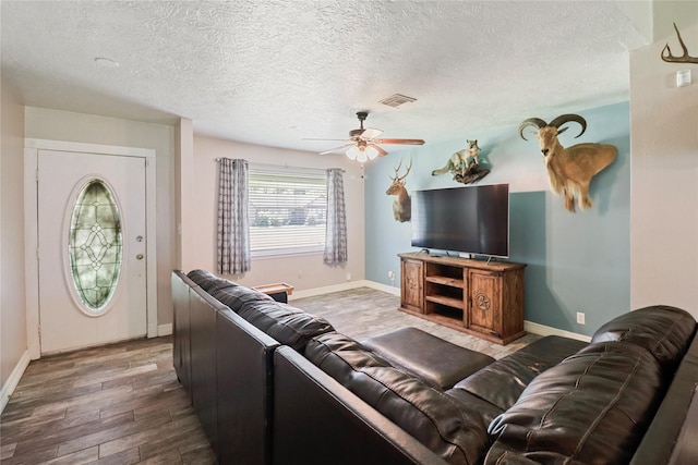 living room featuring a ceiling fan, wood finished floors, baseboards, and a textured ceiling