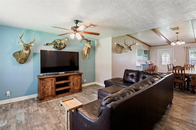 living room with a ceiling fan, wood finished floors, a textured ceiling, a chandelier, and baseboards