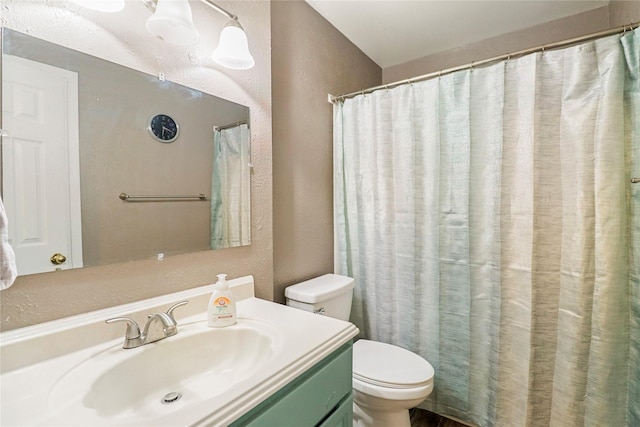 full bathroom with a textured wall, toilet, and vanity