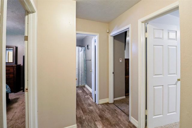 hallway featuring dark wood-type flooring and baseboards