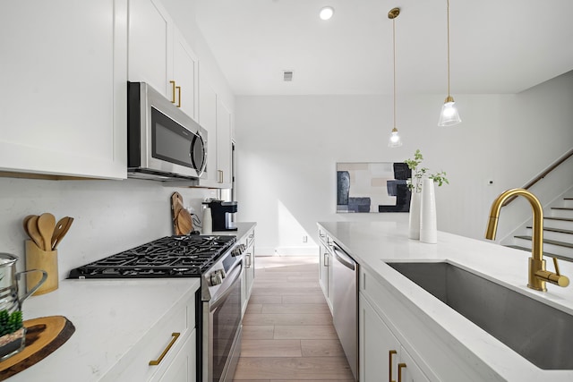 7117 Goforth St, Houston, TX 77021 - kitchen with stainless steel appliances, a sink, light wood-type flooring, white cabinets, and recessed lighting