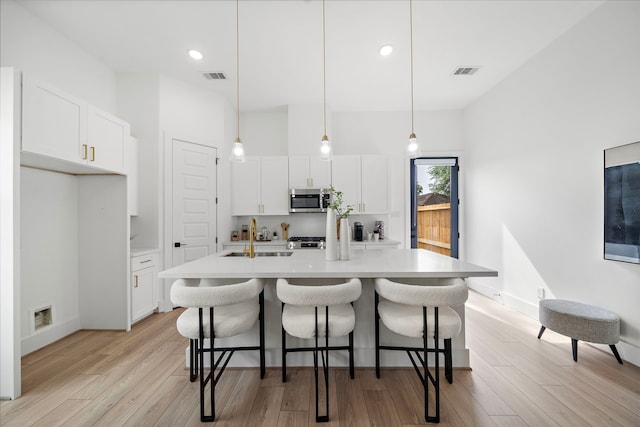 7117 Goforth St, Houston, TX 77021 - kitchen with stainless steel microwave, a sink, light wood finished floors, white cabinets, and recessed lighting