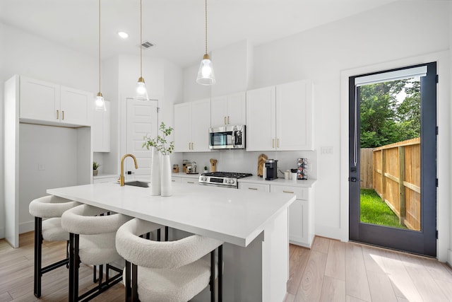 7117 Goforth St, Houston, TX 77021 - kitchen featuring appliances with stainless steel finishes, a sink, light wood-style flooring, white cabinetry, and light countertops
