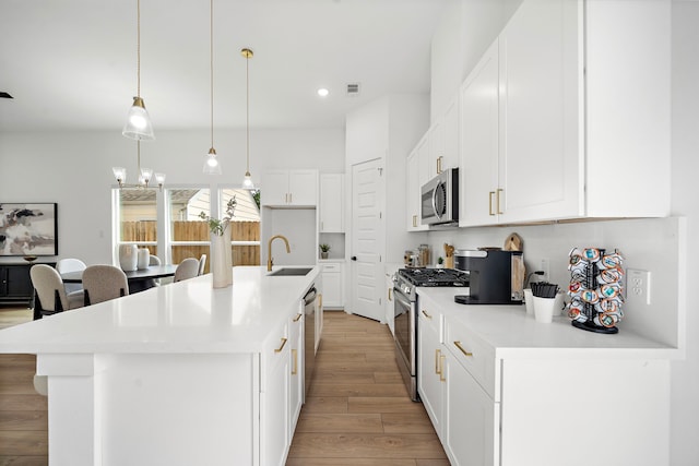 7117 Goforth St, Houston, TX 77021 - kitchen with appliances with stainless steel finishes, a sink, light wood-style floors, a chandelier, and an island with sink